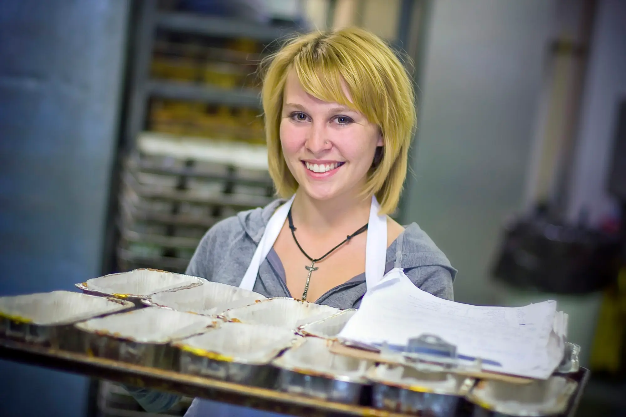 Smiling baker holding a tray of fresh pastries